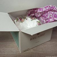 Royal Albert Old Country Roses footed bowl partially wrapped in plastic inside original box with purple rose printed tissue paper.