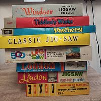 Stacked boxes of various vintage games and puzzles in the lot showing brand names and titles.
