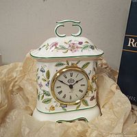 Front view of the bone china clock showing the floral pattern and Roman numeral dial.