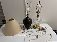 Two table lamps: one with brass base and cut glass body, the other with ceramic body. Extra lampshade and lamp harps.