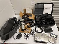 Complete assortment of items on a white table, including a Darkiron percussion massage tool with attachments, a Revlon blow dryer, assorted earbuds, and electronic devices.