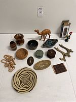 Full lot view showing all items including woven basket, wood mirror, metal rooster, carved camel, brass plate holders, small bowls and puzzles.