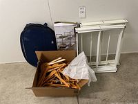 Shows two foldable drying racks, a box of wooden hangers, a navy blue mesh laundry hamper, and the boxed 4-tier metal storage rack.