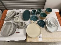 Full lot of mixed ceramic pieces arranged on a white surface showing range of colors and items.
