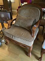 Full view of the oversized armchair showing wooden frame and fabric upholstery with diamond pattern and matching pillow.