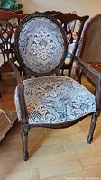 Full view of wood framed chair showing carved legs and upholstered seat with floral pattern