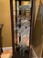 Shelved glassware set showing various stemmed glasses and decanter inside a glass cabinet