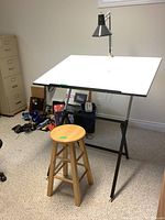 Overall view of drafting table with stool and attached lamp in workspace