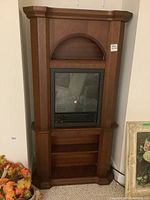 Full view of freestanding wood encased electric fireplace with arch shelf and glass front insert