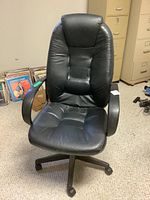 Full view of the black faux leather swivel office chair showing padding, armrests, and swivel base with casters.