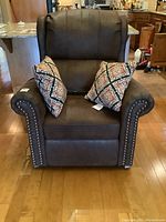 Front view of brown lift recliner with two patterned throw pillows