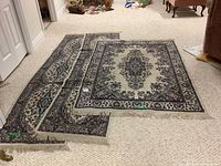 Wide shot of two carpet runners and one rectangular area rug placed adjacent on a beige carpet floor, showing overall condition and pattern.