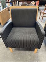 Front view of cushioned armchair with black and white patterned fabric and wooden legs.