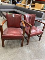 Pair of wood framed chairs with red faux leather seats and backs, showing wear and stud detail around seat edges.