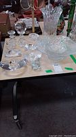 Various clear textured glass items including vase, candleholders, bowls, globe and figurine on table