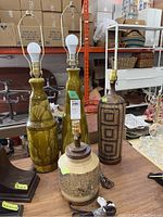 Four lamps grouped together on a table showing the full bodies and bulbs, highlighting different materials and designs.