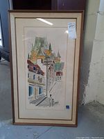 Framed watercolor painting showing a street and castle scene.