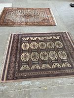Two rugs placed on concrete floor showing design and size relative to each other