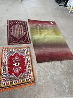 Top-down shot of three rugs laid on concrete floor showing all three rugs' designs and relative sizes.