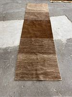 Full length view of the brown gradient runner rug laid on a concrete floor, showing dimensions and pattern.