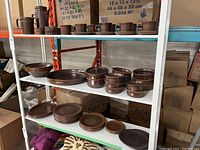 Three shelves displaying brown Wedgwood stoneware including plates, bowls, serving dishes and covered items.
