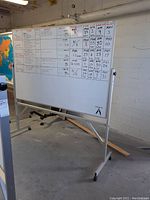 Full view of the large whiteboard with writing visible and metal frame on wheels.