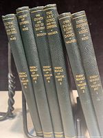 Side view of six books standing vertically, showing gold titles on green spines.