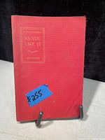 Red hardcover book with embossed gold title 'Shakespeare's As You Like It' on front cover showing mild edge wear and a blue lot sticker.