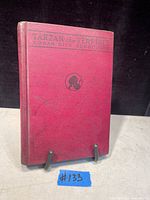 Front cover of the antique book 'Tarzan the Terrible' with red cover and title embossed.