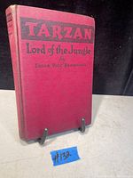 Front cover of red hardcover book titled 'Tarzan Lord of the Jungle' by Edgar Rice Burroughs with visible wear and some fading.