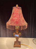 Full view of the antique table lamp showing the copper patina base and floral fabric shade with bead fringe.