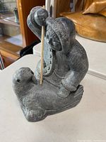 Front angle showing Inuit figure holding a stick above seal.