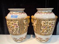Pair of large Asian-style porcelain vases showing front view with detailed bird and floral designs and tiger head handles.