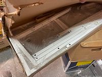 Photo showing white metal shelf panels in original packaging, new condition with plastic wrap and cardboard box.