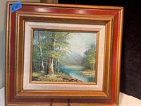 Framed oil painting showing entire painting and frame with reddish gold wooden frame and inner linen mat.