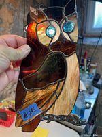 Stained glass owl suncatcher held upright in hand showing glass colors and metal leading details
