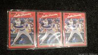 Three identical Andre Dawson baseball cards from 1990 Donruss set in plastic sleeves laid on dark surface.