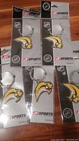 Photo showing five new sealed Buffalo Sabres keychains featuring yellow and blue team logo in original JF Sports packaging.