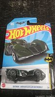 Front view of the Hot Wheels Batman Arkham Asylum Batmobile in packaging showing car and branding details.
