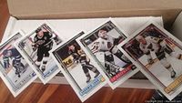 Photo showing several hockey cards in a box, highlighting different players in action poses with team colors and white borders