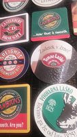 Photo shows detailed view of several beer coasters including Canterbury Draught, Lambrtons, Speight's, Temno Laško, Pivovarna Laško