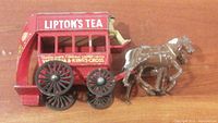 Side view of the red vintage diecast horse-drawn wagon with Lipton's Tea graphics and two brown horses