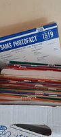 Box showing top edges of colorful vintage Sams Photofact booklets labeled with set numbers like 1519, featuring repair and parts information.