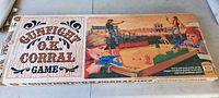 Box top of 1973 Gunfight at O.K. Corral game with illustrated cowboys and western duel scene, wood plank background design