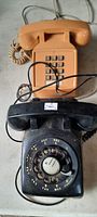 Photo showing two old landline phones: one black rotary dial phone and one beige push-button phone with wiring.