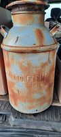 Full view of antique steel milk can showing overall rust and embossed 'CLOVERLAND FARMS' lettering on the front.