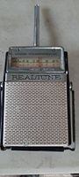 Front view of antique Realtone transistor radio with antenna extended and visible tuning dial.