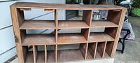Front view of the wooden sectional unit showing multiple cubby compartments and slots. Surface is dusty and wood is lightly worn.