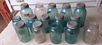 Photo showing all 15 Ball Mason jars arranged together on a table, variety of sizes and aqua-blue and clear glass, all with either metal lids or without lids.