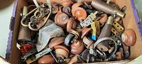 Close-up photo of the assorted hardware and furniture knobs in a cardboard box showing a variety of wooden and metal knobs, drawer pulls, and other pieces.